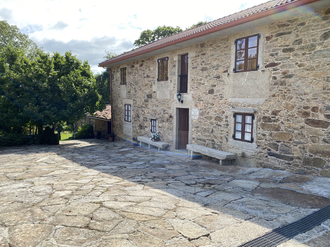 Fachada de A Casa do Muiñeiro rodeada de vegetación en O Allo